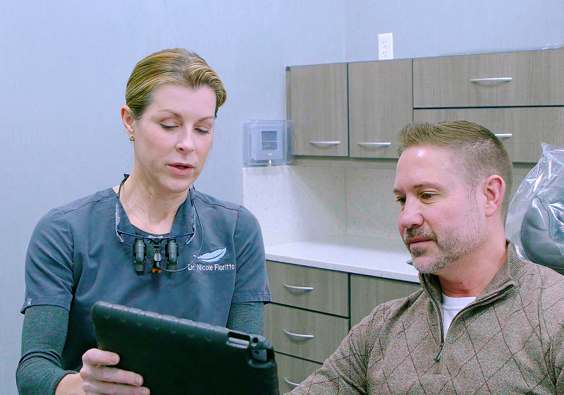 A male patient looking at an Ipad screen with a female staff member in the exam room to discuss dental implant options at Fioritto Family Dental in OH.