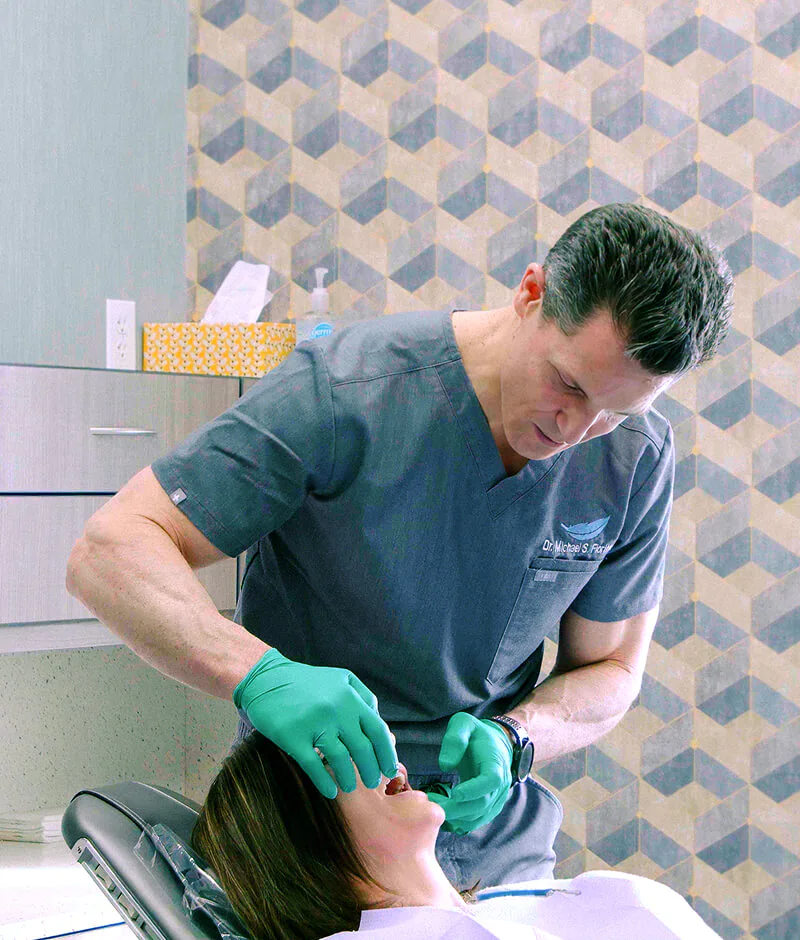 The dentist at Fioritto Family Dental standing over a female patient looking at her teeth in the exam chair in OH.