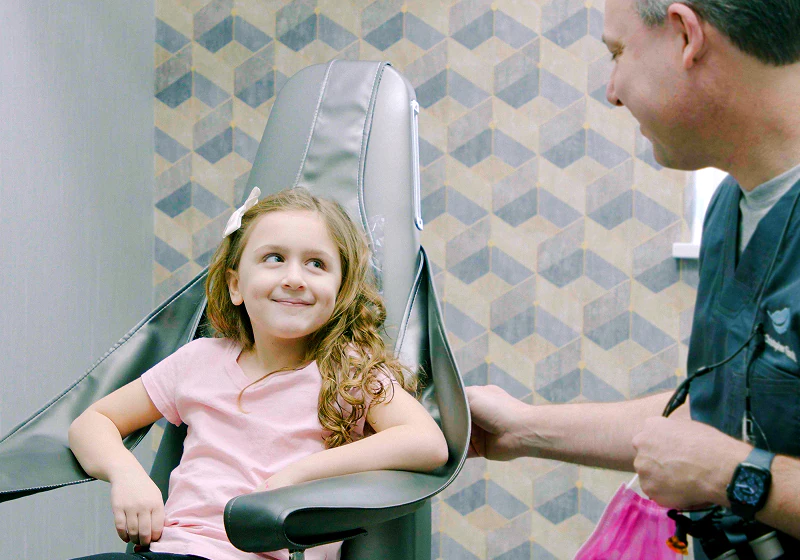 A young child in the exam chair smiling at a staff member at Fioritto Family Dental in Ohio.